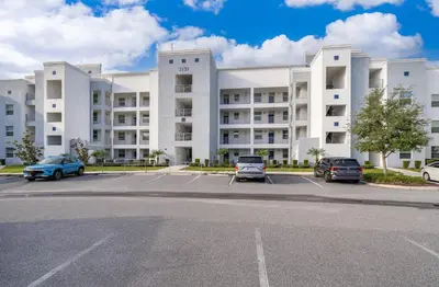a large white building with cars parked in a parking lot at 3131-403AR STOREY LAKE, CONDO 2/2 LAKE VIEW in Kissimmee