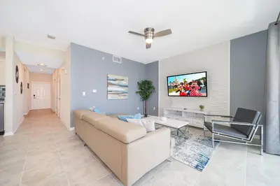 a living room with a couch and a tv on a wall at 3141-202RF STOREY LAKE, CONDO 2/2 LAKE VIEW in Kissimmee