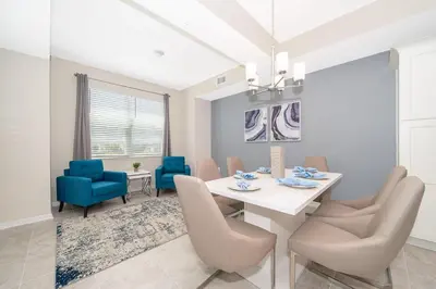 a dining room with a white table and blue chairs at 3141-202RF STOREY LAKE, CONDO 2/2 LAKE VIEW in Kissimmee