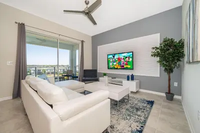 a living room with white furniture and a flat screen tv at 3141-405IL STOREY LAKE, CONDO 2/2 LAKE VIEW in Kissimmee