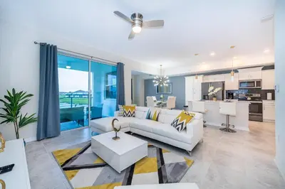 a living room with a white couch and a kitchen at 3131-202JQ STOREY LAKE, CONDO 2/2 LAKE VIEW in Kissimmee