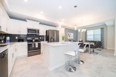 a kitchen with white cabinets and a table and chairs at 3151-307BE STOREY LAKE, CONDO 2/2 LAKE VIEW in Kissimmee