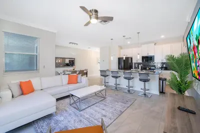 a living room with a white couch and a kitchen at 4381FA TOWNHOUSE 4 BEDROOMS & 3 BATHROOMS + POOL in Kissimmee