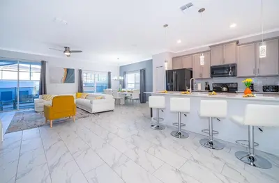 a large kitchen and living room with a yellow chair at 3005PB TOWNHOUSE 5 BEDROOMS & 4 BATHROOMS + POOL in Kissimmee