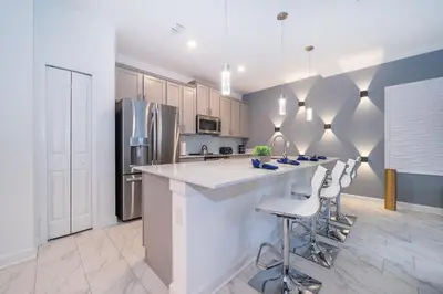 a kitchen with a large counter and stools at 4202MC TOWNHOUSE 4 BEDROOMS & 3 BATHROOMS + POOL in Kissimmee