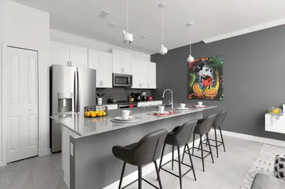 a kitchen with a counter with chairs and a refrigerator at Last Minute Disney Getaway Private Pool Themed Bedrooms. Book Now 56757 in Kissimmee