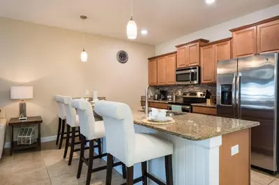 a kitchen with a counter with bar stools and a refrigerator at Last Minute Disney Getaway! Private Pool, Hot Tub & Games Room. Book Now! #17074 in Kissimmee