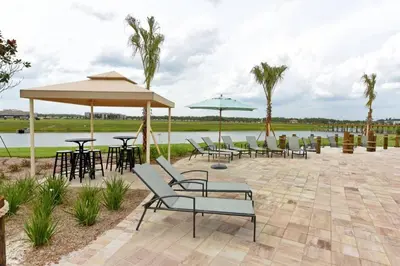 a patio with chairs and umbrellas next to a lake at Last Minute Disney Getaway Private Pool Themed Bedrooms. Book Now 17142 in Kissimmee