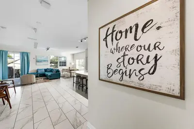 a living room with a sign that reads home where our story begins at Roomy Family Home-Sleeps 16 STL110 in Kissimmee