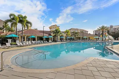 a large swimming pool with chairs and palm trees at Epic Location 3BR Home w Full Comfort in Orlando