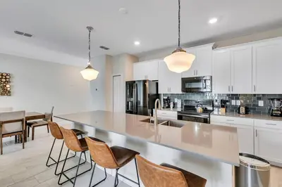 a kitchen with white cabinets and a counter with chairs at Stylish Family Home - Private Pool - STL111 in Kissimmee