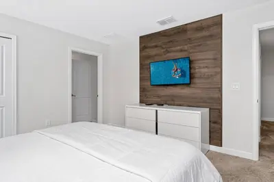 a bedroom with a white bed and a tv on a wall at Really close to Disney! Sleeps 10 - STL116 in Kissimmee
