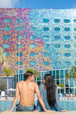 a man and a woman sitting next to a pool at Universal's Stella Nova Resort in Orlando