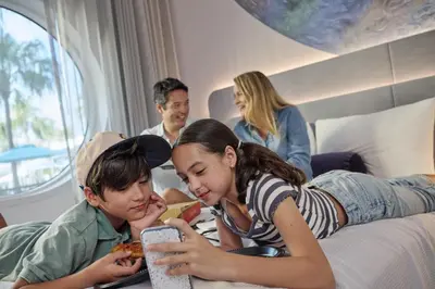 two girls and a boy laying on a bed eating pizza at Universal's Terra Luna Resort in Orlando