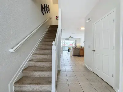 a hallway with white walls and stairs with a door at Sunnyside Up Gated Resort Style Community in Orlando
