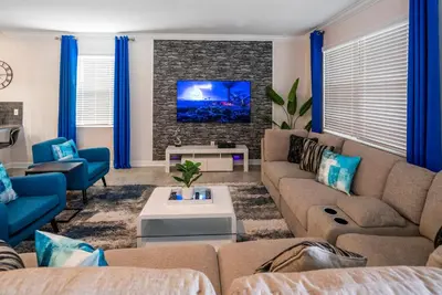 a living room with couches and a tv at Luxury Lake View 9-Bedroom Villa @Storey Lake Resort in Kissimmee