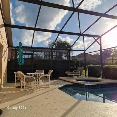 a patio with a table and chairs and a pool at Florida Jewels - beautiful villa on Emerald Island in Kissimmee