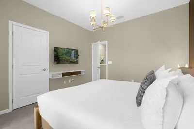 a white bedroom with a white bed and a chandelier at 30-Guest Home w Theme Rooms Games Resort Access in Kissimmee