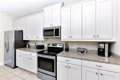 a white kitchen with white cabinets and appliances at Glorious Home Near Disney With Private Pool, Game Room And Waterpark & Resort Access At Encore Resorts Reunion - 660La in Kissimmee
