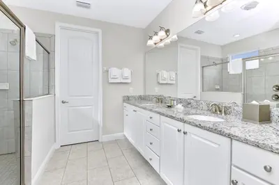a white bathroom with two sinks and a shower at Stylish Home With Themed Rooms, Game Room And Waterpark & Resort Access Near Disney At Encore Resorts Reunion - 267Sf in Kissimmee
