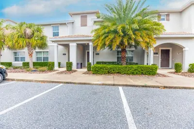 a house with palm trees in front of a street at Amazing Townhouse at Storey Lake Resort in Kissimmee