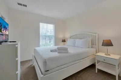 a white bedroom with a white bed and a window at Esmerald Island Resort Oasis: Your Perfect Getaway Near Disney in Kissimmee