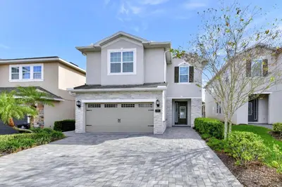 a large white house with a garage at Cheerful Home Near Disney With Private Pool, Themed Rooms And Waterpark & Resort Access At Encore Resorts Reunion - 7394Mr in Kissimmee