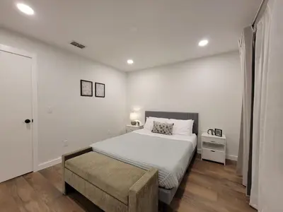 a white bedroom with a bed and a chair at Elegant Cozy Spot to unwind! UCF/MCO/Parks/Beach in Orlando