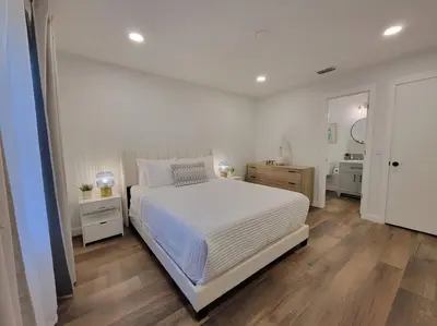 a bedroom with a large white bed and wooden floors at Elegant Cozy Spot to unwind! UCF/MCO/Parks/Beach in Orlando
