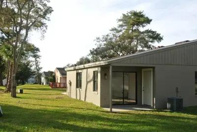 a small white building next to a grass yard at Elegant Cozy Spot to unwind! UCF/MCO/Parks/Beach in Orlando