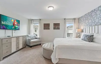 a bedroom with a bed and a tv and a chair at Amazing 6Bdrms At Storey Lake- Close to Disney in Kissimmee