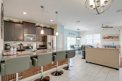 a kitchen and living room with a counter and chairs at Kissimmee Getaway with Pool Access 5 Mi to Disney in Kissimmee