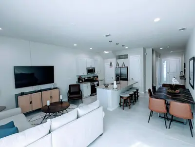 a living room with a white couch and a kitchen at Cozy 2024 New 3 Suites 5 min to Disney in Orlando