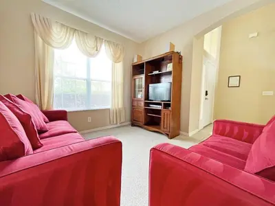 a living room with two red couches and a television at Sunnyside Villa home in Kissimmee