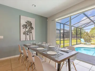 a dining room with a table and chairs and a pool at 6BR w Heated Pool + 9MI to Disney + Sleeps 14 in Kissimmee