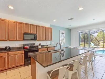 a kitchen with wooden cabinets and a counter top at 6BR w Heated Pool + 9MI to Disney + Sleeps 14 in Kissimmee