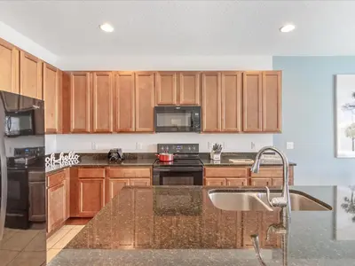 a kitchen with wooden cabinets and a counter top at 6BR w Heated Pool + 9MI to Disney + Sleeps 14 in Kissimmee