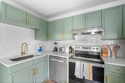 a kitchen with green cabinets and a stove top oven at Fire Pit + Grill + 2MI to DT Orlando in Orlando