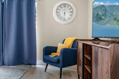 a living room with a blue chair and a clock at 4BR w Heated Pool near Disney & Lake - Sleeps 10 in Kissimmee