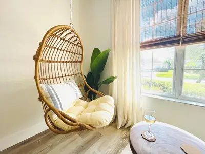 a hanging rattan chair in a room with a window at Enchanted Hideaway in Kissimmee