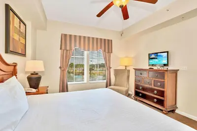 a bedroom with a bed with a ceiling fan and a window at Cozy 2BR Condo Resort Spa with Pirate Pool in Kissimmee