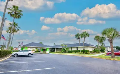 a car parked in front of a building with palm trees at Pool - WiFi - Parking - Best Location ! in Kissimmee