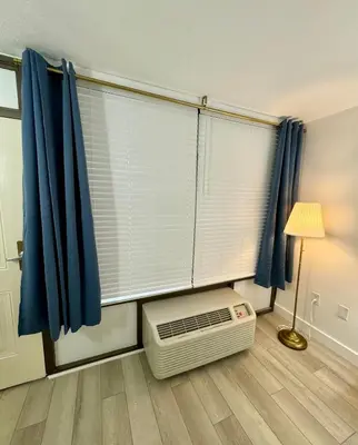 a room with a window with blue curtains and a heater at Pool - WiFi - Parking - Best Location ! in Kissimmee