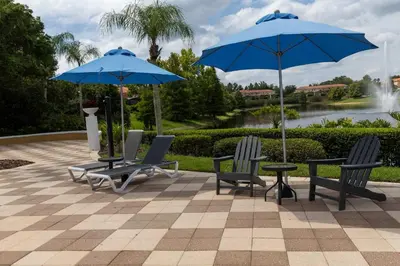 two blue umbrellas and two chairs and a table at Beautiful Townhome w Hot Tub Near Disney in Kissimmee