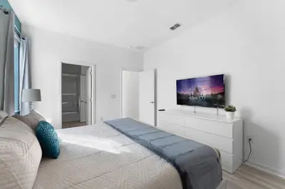 a white bedroom with a large bed with a flat screen tv at Last Minute Disney Private Pool Hot Tub Game Room Themed Bedrooms. Book Now 43123 in Kissimmee