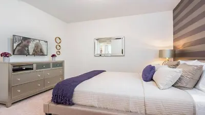a bedroom with a bed and a dresser with a mirror at Last Minute Disney Getaway! Private Pool, Hot Tub & Games Room. Book Now! #60535 in Orlando