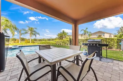 a patio with a table and chairs and a grill at Last Minute Disney Getaway! Private Pool, Hot Tub & Games Room. Book Now! #39430 in Orlando