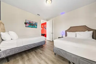 two beds in a room with white walls and wooden floors at Last Minute Disney Getaway! Private Pool, Hot Tub & Games Room. Book Now! #39430 in Orlando