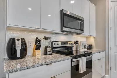 a kitchen with white cabinets and a stove top oven at Last Minute Disney Getaway Private Pool Themed Bedrooms. Book Now 81937 in Orlando
