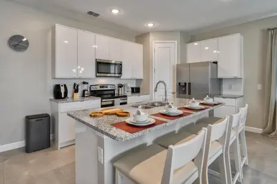 a kitchen with white cabinets and a large island with chairs at Last Minute Disney Getaway Private Pool Themed Bedrooms. Book Now 81925 in Orlando